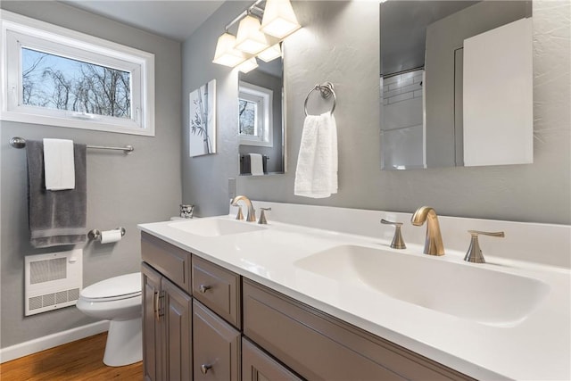 full bath with double vanity, wood finished floors, a sink, and toilet