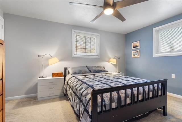 bedroom featuring light colored carpet, ceiling fan, baseboards, and multiple windows