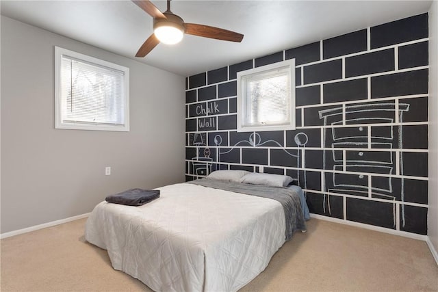 carpeted bedroom featuring an accent wall, baseboards, and a ceiling fan