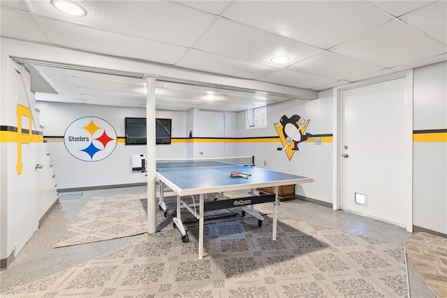 recreation room with baseboards and a drop ceiling