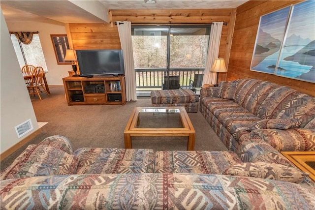 living room with wood walls, baseboards, visible vents, and carpet flooring