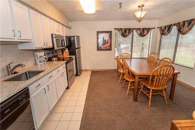 kitchen featuring light tile patterned floors, stainless steel appliances, a sink, white cabinetry, and decorative backsplash