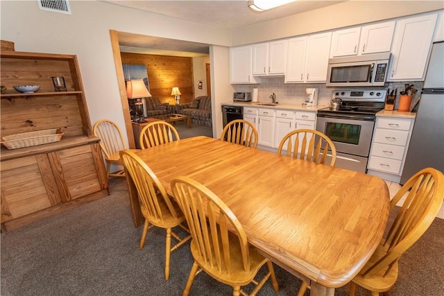 kitchen featuring stainless steel appliances, a sink, visible vents, white cabinetry, and decorative backsplash