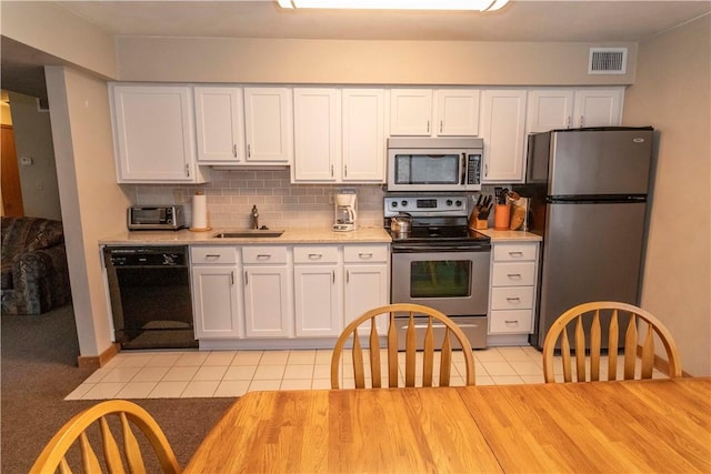 kitchen with a sink, visible vents, light countertops, appliances with stainless steel finishes, and decorative backsplash