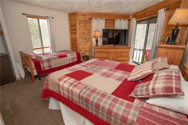 bedroom featuring access to outside, visible vents, wooden walls, and carpet