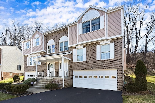 raised ranch with an attached garage, aphalt driveway, and brick siding