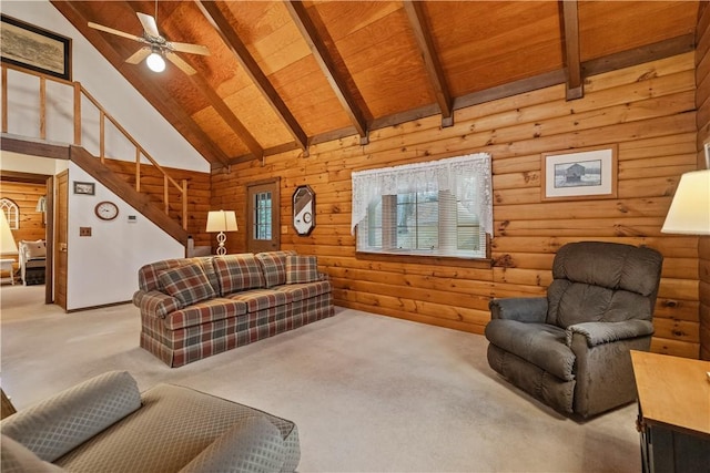 carpeted living area with ceiling fan, high vaulted ceiling, wooden ceiling, stairs, and beamed ceiling