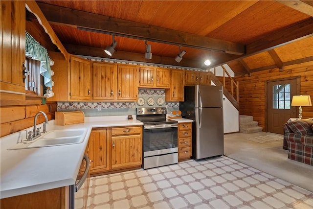 kitchen with wooden walls, stainless steel appliances, a sink, light countertops, and light floors