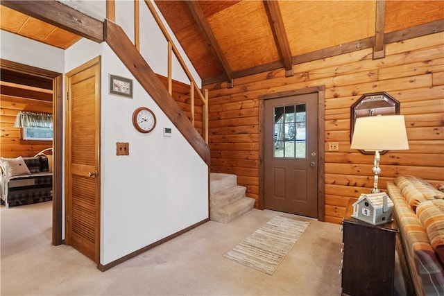 entryway with lofted ceiling with beams, stairs, and carpet flooring