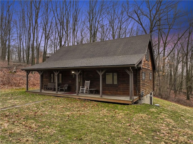 view of front facade featuring covered porch, a shingled roof, and a front lawn