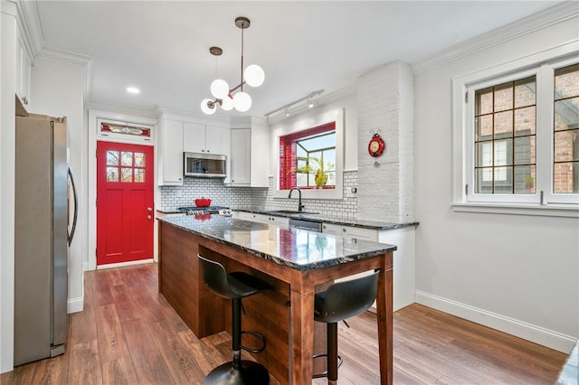 kitchen with stainless steel appliances, dark wood finished floors, crown molding, and backsplash