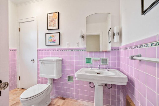 half bath featuring toilet, a wainscoted wall, tile walls, and tile patterned floors