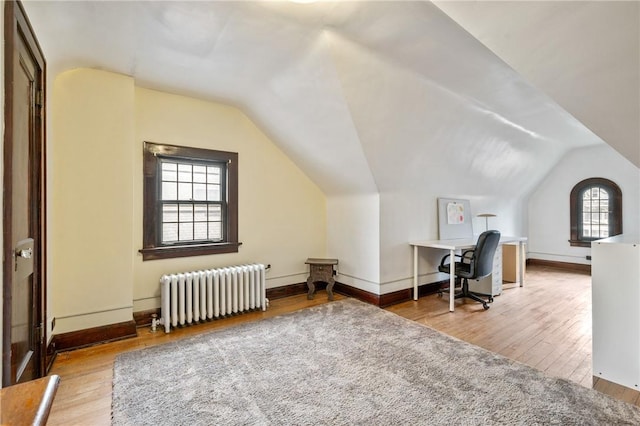 office with lofted ceiling, baseboards, wood finished floors, and radiator