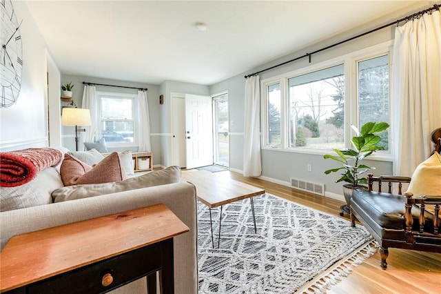 living area with light wood-type flooring, visible vents, and baseboards