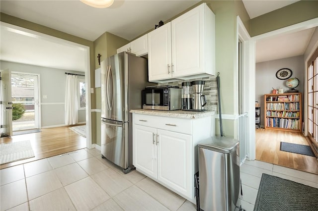 kitchen with stainless steel appliances, white cabinets, light tile patterned flooring, and decorative backsplash