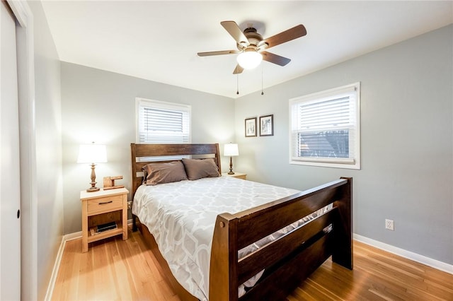 bedroom with a ceiling fan, light wood-style flooring, and baseboards