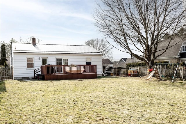 rear view of house with a chimney, a lawn, metal roof, a deck, and fence private yard