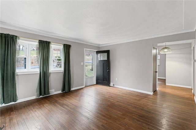 empty room with wood-type flooring, visible vents, and baseboards