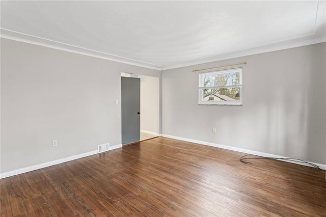 unfurnished room featuring hardwood / wood-style floors, visible vents, and baseboards