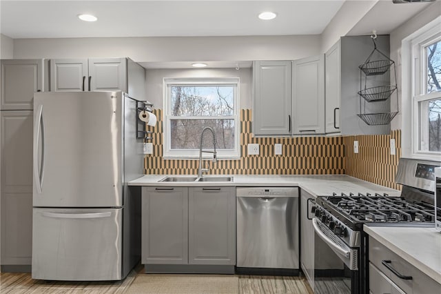 kitchen featuring appliances with stainless steel finishes, gray cabinets, a sink, and light countertops