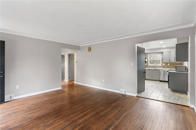 unfurnished living room with visible vents, light wood-style flooring, and baseboards