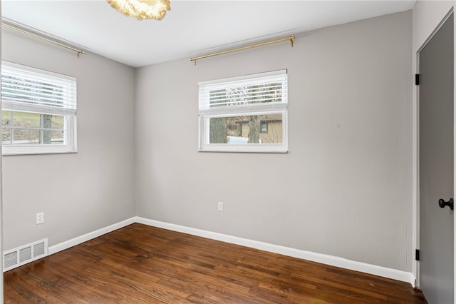 empty room with baseboards, visible vents, and wood finished floors