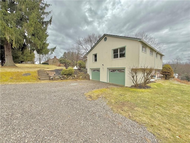 view of side of property with driveway, an attached garage, and a lawn