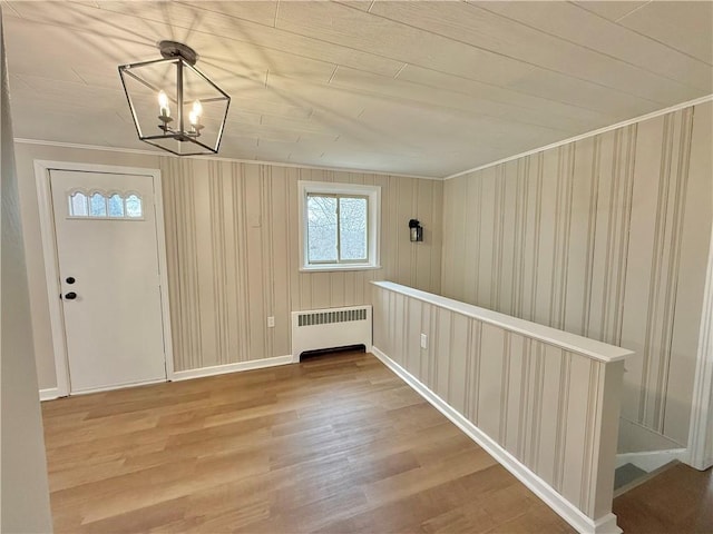 entryway featuring crown molding, radiator, a notable chandelier, and wood finished floors