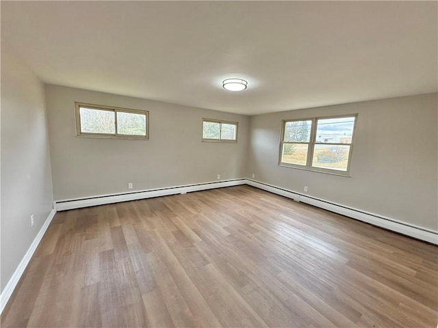 empty room featuring baseboard heating, wood finished floors, and baseboards