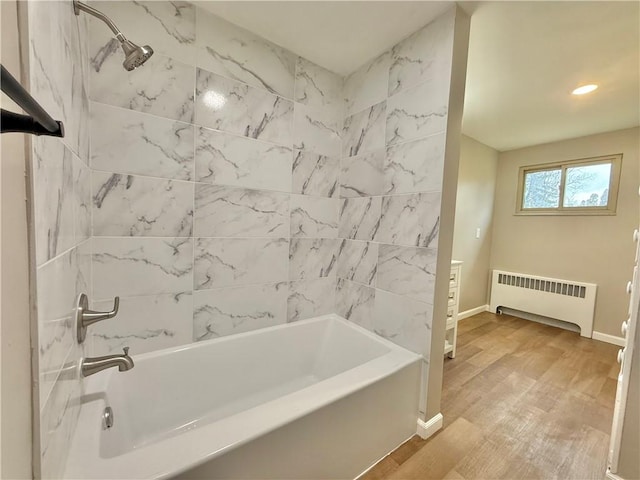 bathroom with radiator, tub / shower combination, baseboards, and wood finished floors