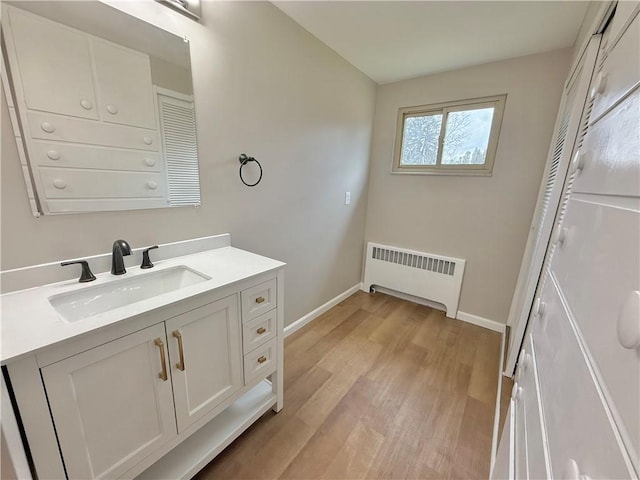 bathroom with radiator, vanity, baseboards, and wood finished floors