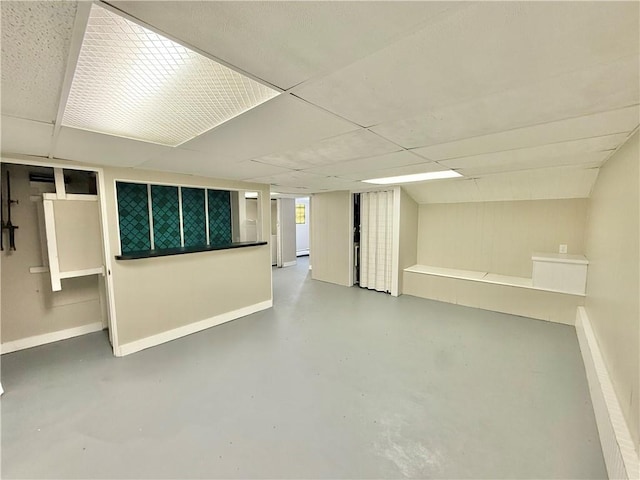 finished below grade area featuring a drop ceiling and baseboards