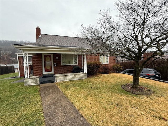 view of front of house featuring roof with shingles, a chimney, a front lawn, and brick siding