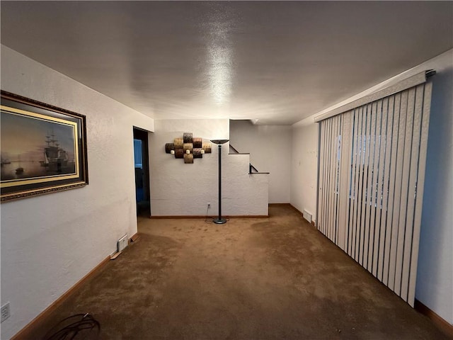 finished basement with carpet, visible vents, and a textured wall