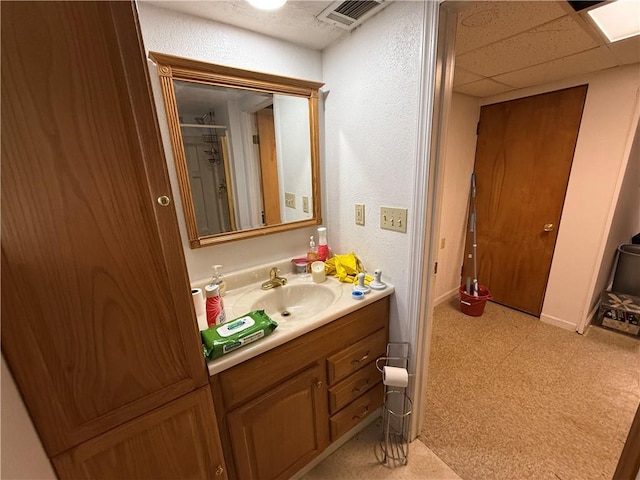 bathroom with a drop ceiling, visible vents, vanity, and tile patterned floors