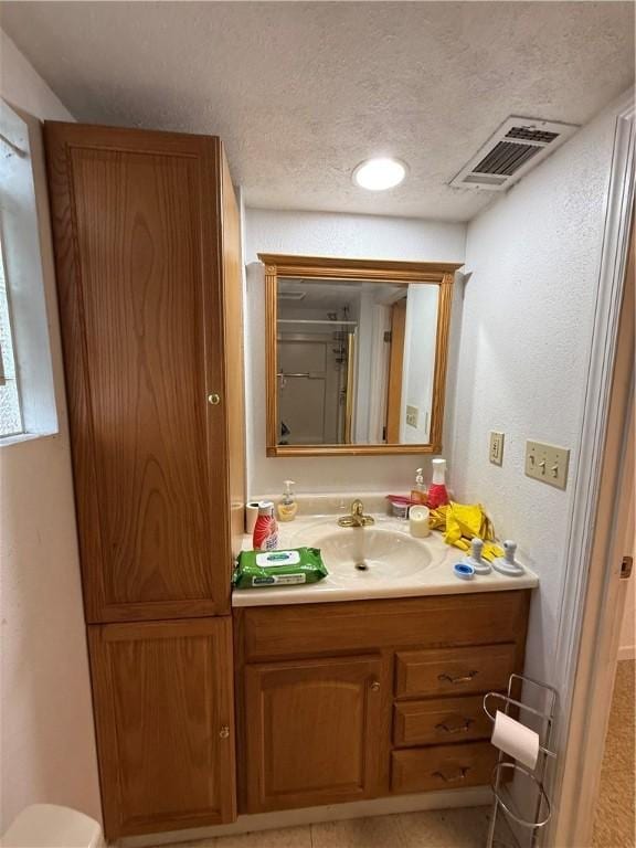 bathroom with a textured ceiling, vanity, and visible vents