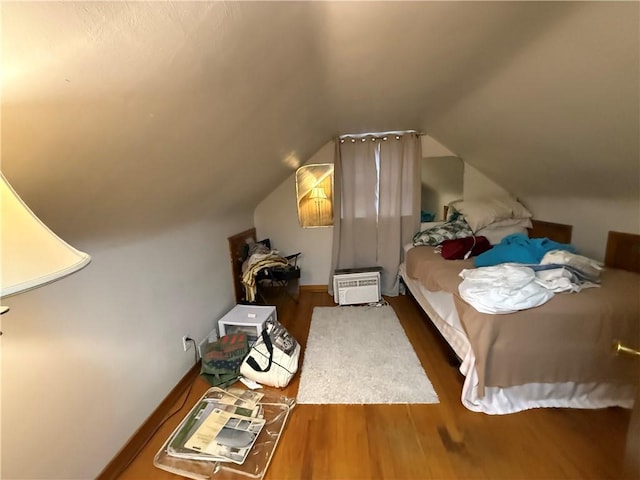 bedroom with vaulted ceiling and wood finished floors