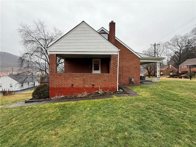 view of property exterior featuring crawl space, brick siding, a yard, and a chimney