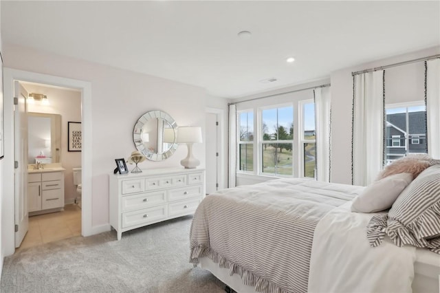 bedroom featuring light tile patterned floors, baseboards, connected bathroom, light colored carpet, and a sink