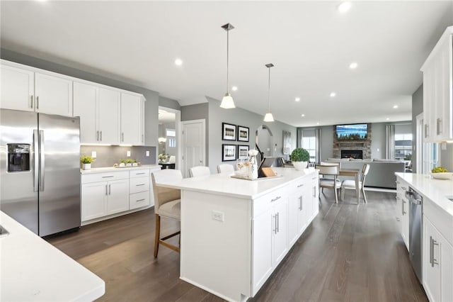 kitchen with dark wood-style floors, a kitchen island, stainless steel appliances, a fireplace, and white cabinetry