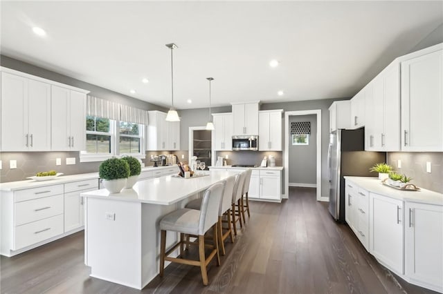 kitchen featuring appliances with stainless steel finishes, a center island, white cabinets, and dark wood finished floors