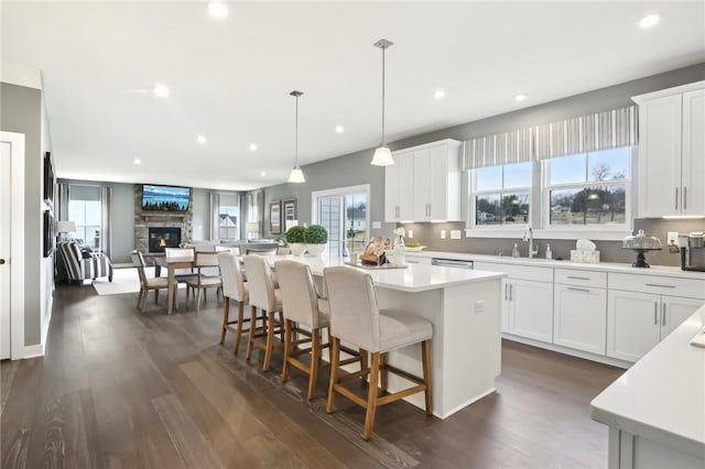 kitchen with open floor plan, light countertops, a stone fireplace, and a sink