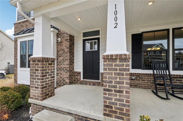 entrance to property with a porch and brick siding