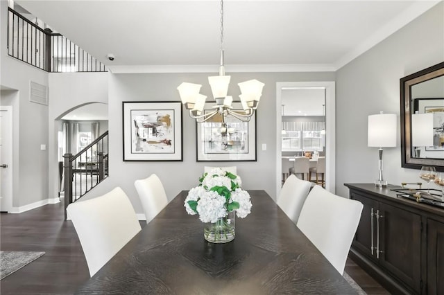 dining area featuring arched walkways, dark wood-type flooring, baseboards, stairway, and an inviting chandelier