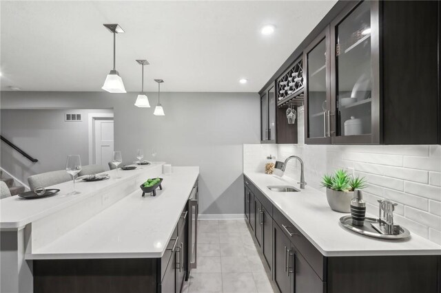 kitchen with visible vents, a sink, a peninsula, and decorative backsplash