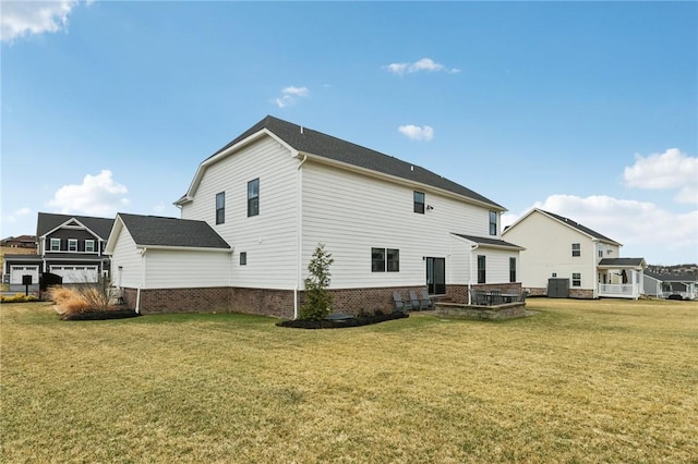 rear view of house with central air condition unit, brick siding, and a yard