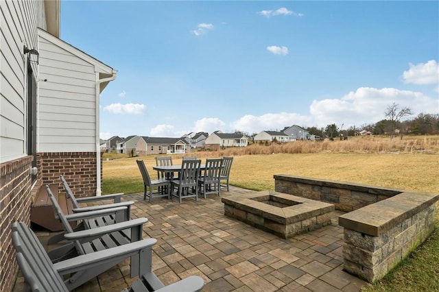 view of patio with an outdoor fire pit, outdoor dining area, and a residential view