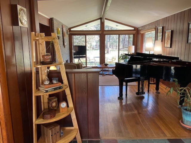 sitting room with wood-type flooring, vaulted ceiling with beams, and wood walls