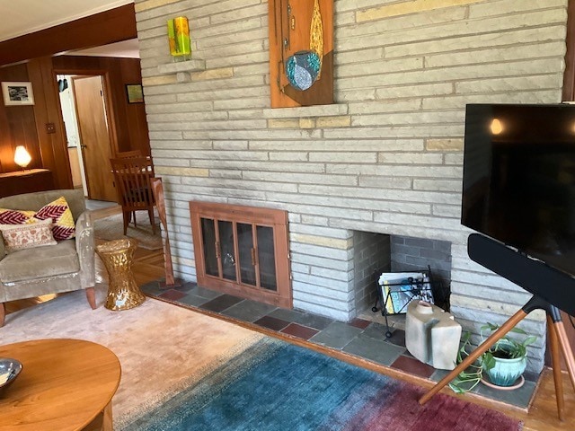 living area with a brick fireplace and wooden walls