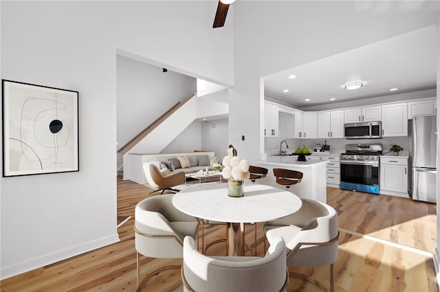 dining room featuring light wood-type flooring, baseboards, a ceiling fan, and recessed lighting